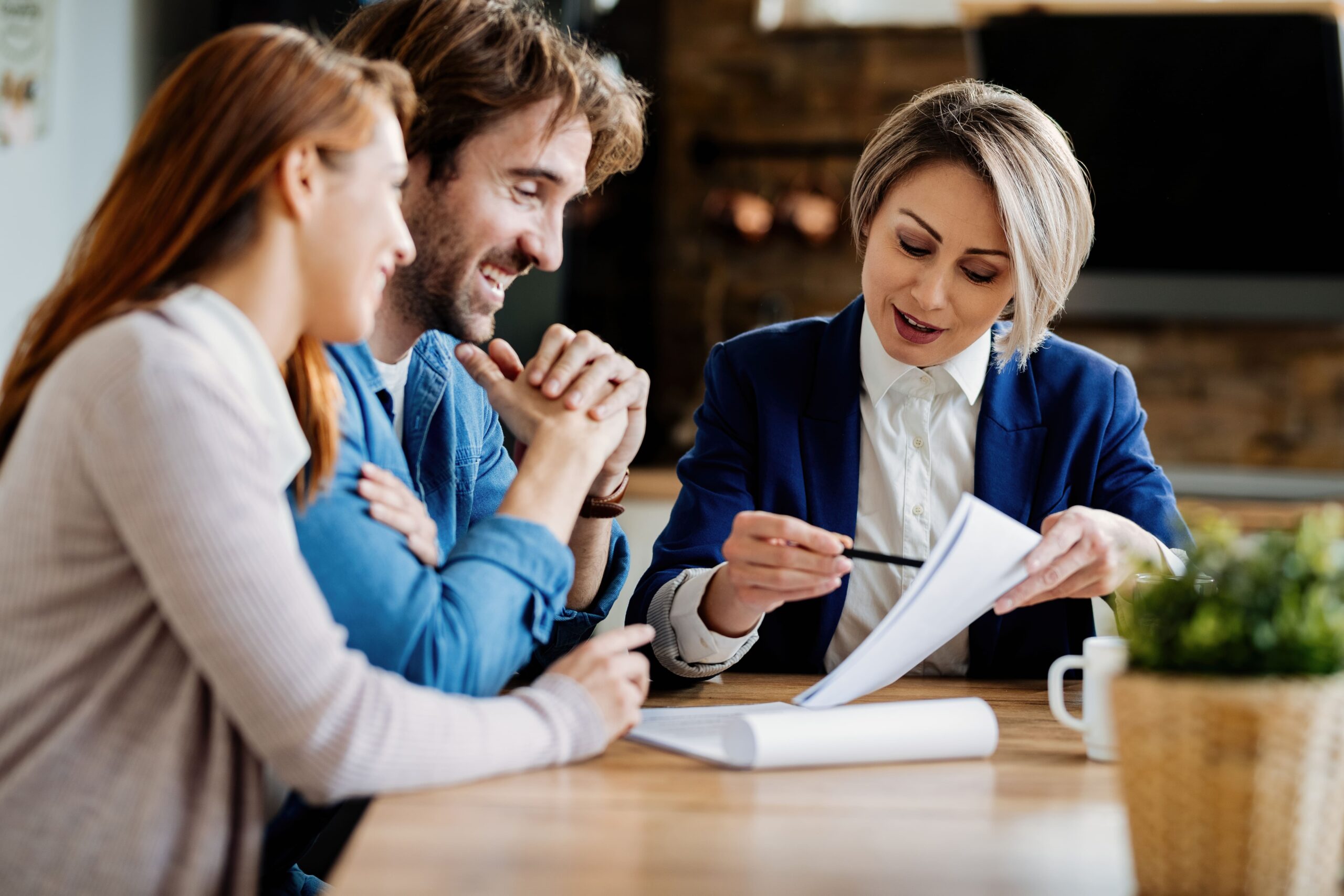 Real estate agent discussing documents with a happy couple at a table.