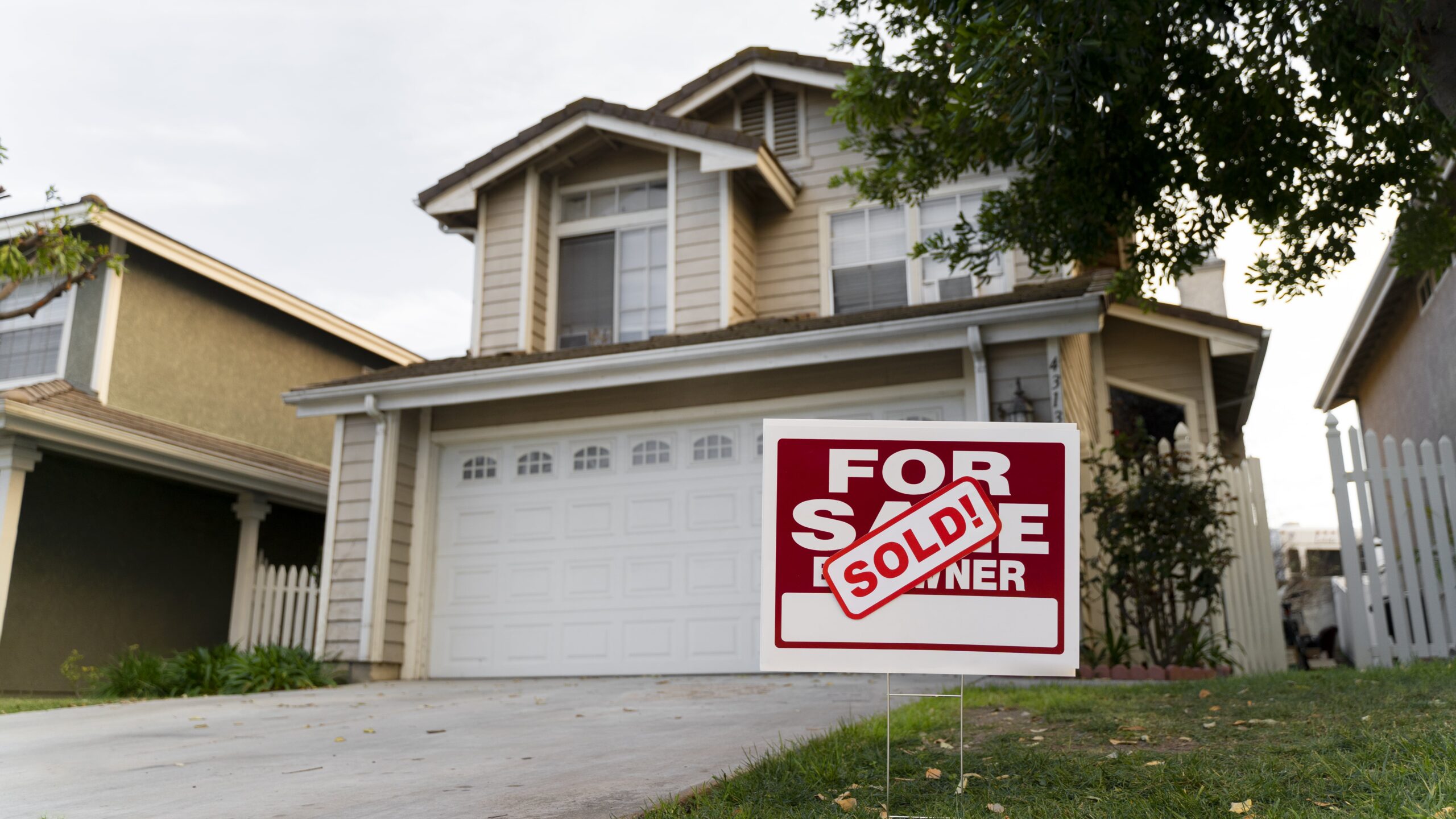 Modern house with 'For Sale' sign displaying 'Sold' in front yard